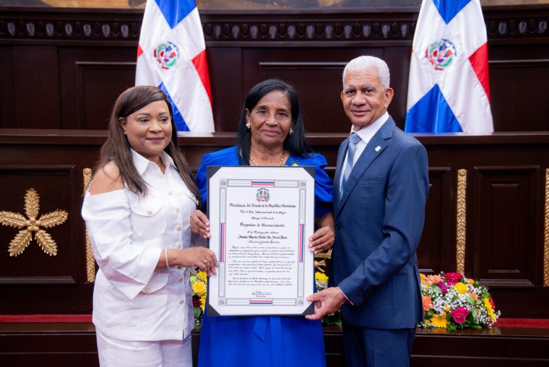 Senado reconoce a 32 mujeres líderes en tercera edición del evento anual “Mujeres que Transforman” SANTO DOMINGO. – Con motivo de conmemorarse este domingo ocho de marzo el Día Internacional de la Mujer, el Senado de la República reconoció a 32 mujeres de las 31 provincias del país y el Distrito Nacional, por su liderazgo y aportes al desarrollo del país en los renglones de educación, salud, cultura, deporte, emprendimiento, servicio comunitario, gestión pública y labor social. La entrega de lauros, realizada en el marco de la tercera edición del evento, que este año lleva por eslogan “Huellas de Futuro: Mujeres que Transforman”, se realiza como una forma de rendir tributo a la entrega silenciosa, el liderazgo firme y la trayectoria fructífera de insignes líderes femeninas del país que han contribuido al desarrollo social y económico de sus respectivas comunidades. El acto solemne se llevó a cabo en el salón de la Asamblea Nacional y fue encabezado por el presidente del Senado, Ricardo de los Santos, quien en su discurso resaltó que, con estos reconocimientos, el órgano legislativo reafirma su compromiso con una sociedad donde el talento femenino tenga igualdad de oportunidades, donde la seguridad y el respeto sean garantías reales, y donde el liderazgo de las mujeres continúe fortaleciendo la democracia. El legislador destacó que un país que honra y respeta a sus mujeres también honra su conciencia y fortalece su democracia. “Hoy, el Senado de la República no solo reconoce a mujeres destacadas, también reconoce el corazón mismo de la nación. Que Dios las bendiga a todas”. En la actividad también habló la senadora Aracelis Villanueva, quien además preside la Comisión Permanente de Asuntos de Familia y Equidad de Género del Senado. En su discurso sostuvo que este reconocimiento anual, que distingue a una mujer por cada provincia, es una expresión clara de visión institucional impulsada por el presidente del Senado, Ricardo de los Santos, quien ha reflejado un liderazgo con sensibilidad que demuestra gran comprensión de la historia y el compromiso con la equidad. “Bajo su dirección, la Cámara Alta no solo legisla, también honra, educa y construye referentes nacionales, y eso fortalece la democracia con coherencia y convicción”, dijo la congresista. En representación de las homenajeadas, la doctora Yanet Elizabeth Cedeño Rijo, de la provincia La Altagracia, agradeció al Senado por distinguir a tantas mujeres valiosas de la República Dominicana, “quienes trabajan cada día sin descanso: ellas son emprendedoras, profesionales, comerciantes, educadoras, agricultoras, madres jóvenes soñadoras y adultas sabias que sostienen el presente y moldean el futuro”. Las 32 mujeres que fueron reconocidas recibieron sus pergaminos junto a los senadores que las propusieron para ser distinguidas. En el área de la educación recibieron sus pergaminos de reconocimiento Aura Luisa Carrasco de Peña, de Barahona; María Mercedes Odilin Morel, de Duarte; Emérita Aurora Rincón Mojica, de El Seibo; María Reina de los Ángeles Camilo, de Espaillat; y Nurys García de Papaterra, de Hato Mayor. También María Carolina del Pilar Gómez Grullón, de Montecristi; Adalberta Lucía Calcaño Maldonado, de Samaná; Ana Altagracia Rodríguez González, de Monte Plata; Amatista Míriam Pujols Feliz, de San José de Ocoa; Alfonsina de la Rosa Vidal, de San Juan; y Juana María Paula de Jesús Sosa, de Sánchez Ramírez. En el área de servicio comunitario, Jaqueline Núñez Arismendy, de Bahoruco; Quisqueya de Oleo Angomás, de Elías Piña; Ingrid Maribel Bretón Acosta, de La Romana; Vilma Ricardo Santos, de Puerto Plata; Sonia Alejandra Perozo Barinas, de San Cristóbal; Olga María Noboa Fernández, de Santiago; y Georgina López de Brador, de Santo Domingo. En el renglón de emprendimiento, Yudelka María Rodríguez, de Monseñor Nouel; Evangelista Paulino Pérez, de Peravia; Chela Dioneiry Carpio Flobil, de San Pedro de Macorís; Zoraida Rosanna Castillo Corniel, de Santiago Rodríguez; y Seferina Ventura Abreu, de Dajabón. En el área de labor social recibieron homenaje Sor María Ayala Adames, del Distrito Nacional; Nellys M. Heredia Agramonte, de Azua; Dra. Luz María Santos, de María Trinidad Sánchez; Yildalina Noemí Tatem Brache, de Hermanas Mirabal; y Euranny Samira Molina Jiménez, de Pedernales, entre otras. En gestión política y empresarial recibieron congratulaciones Aminta Vólquez de Pérez, de Independencia; Yanet Elizabeth Cedeño Rijo, de La Altagracia; Rosa Olga Medrano Cosme, de La Vega; y Raquel Minier de Morel, de Valverde. El acto solemne contó con la presencia de Gloria Reyes, ministra de la Mujer; diputados, funcionarios del Gobierno y otras autoridades civiles y militares. Por el Senado de la República estuvieron en la actividad los senadores Daniel Rivera, Pedro Catrain, Lía Díaz de Díaz, María Mercedes Ortiz, Odalis Rodríguez, Julito Fulcar, Pedro Tineo, Augusto Velázquez, Ramón Rogelio Genao, Héctor Acosta, Aneudy Ortiz Sajiun, Eduar Alexis Espíritusanto, Rafael Barón Duluc Rijo, Franklin Romero, Manuel María Rodríguez y Moisés Ayala. Por Elvis Castro Hernández 05-03-2026